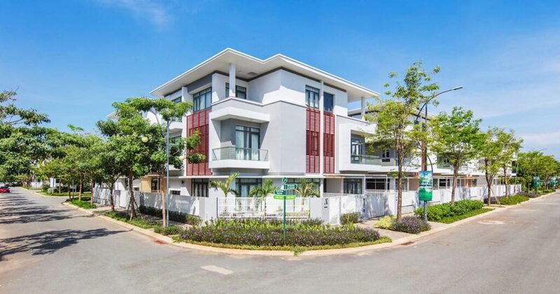 Hình ảnh nhà đất hiện đại ba tầng nằm ở góc đường, bao quanh bởi cây xanh và không gian yên tĩnh